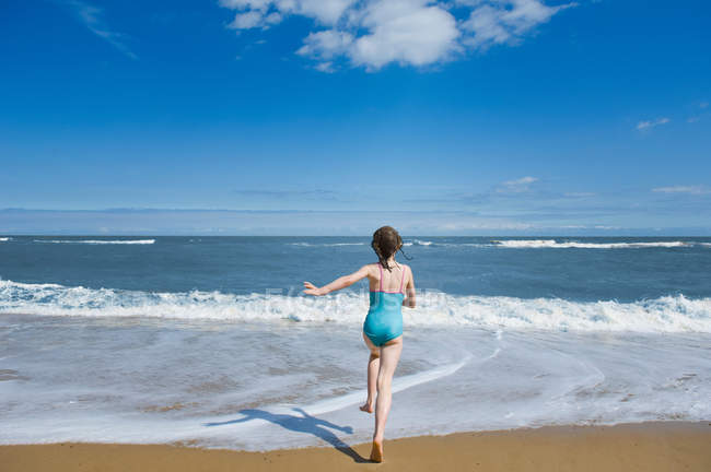 Вид сзади маленькой девочки, бегущей в море — стоковое фото