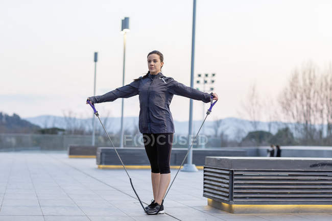 Jeune femme faisant de l'exercice à l'extérieur, en utilisant une corde à étirer — Photo de stock