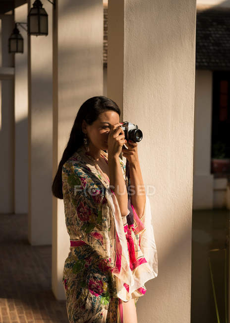 Mujer tomando fotografías por columnas en el hotel - foto de stock