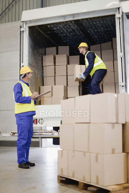 Рабочие разгружают коробки из грузовиков — стоковое фото