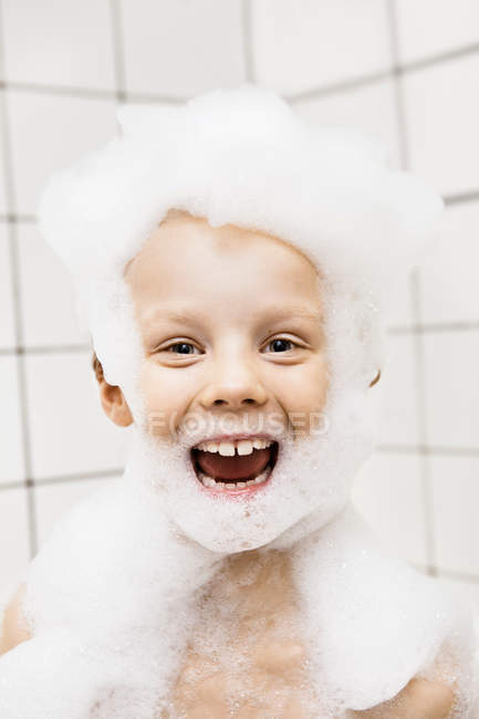 Хлопчик грає з бульбашками у ванні, фокус на передньому плані — стокове фото
