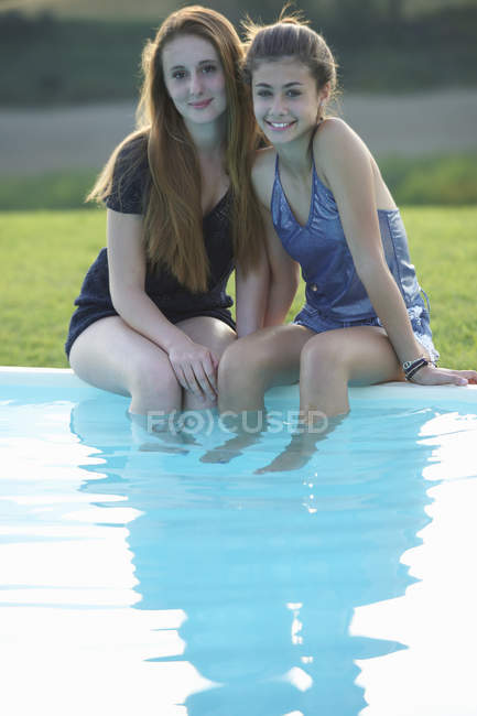 Two teenage girls sitting at poolside — Stock Photo