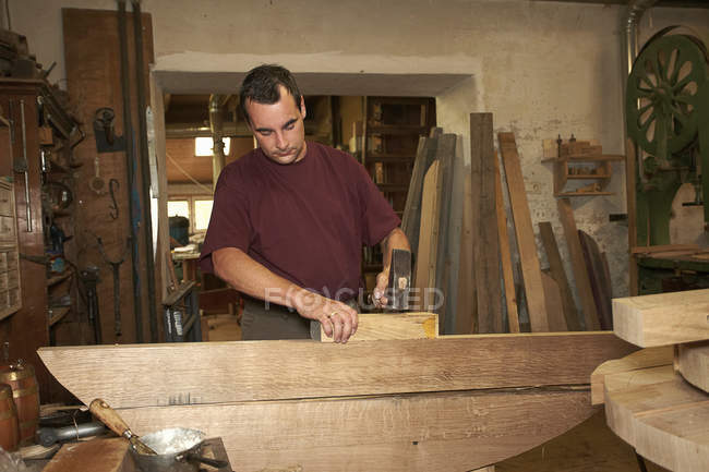 Trabajador martillando madera en tienda - foto de stock