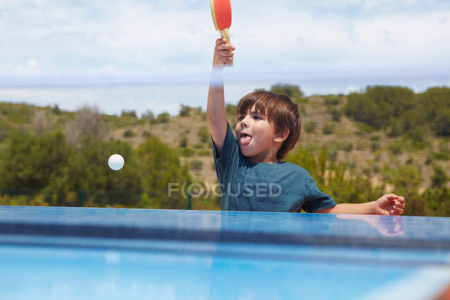 Jeune garçon jouant au tennis de table en plein air — Photo de stock