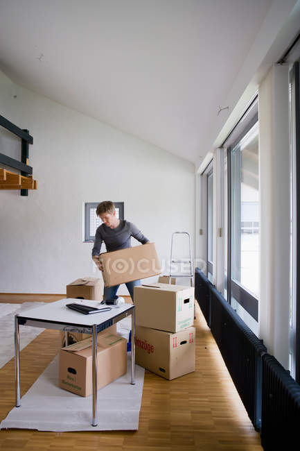 Man stacking cardboard boxes in house — Stock Photo