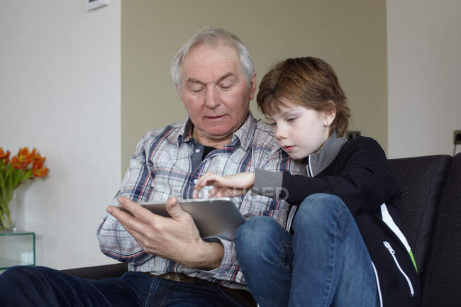 Homme âgé avec petit-fils utilisant une tablette numérique à la maison — Photo de stock