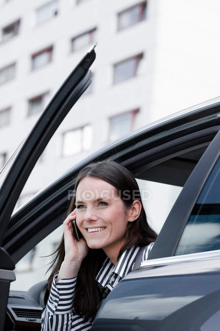 Woman sitting in car and talking on phone — Stock Photo