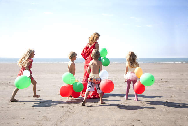 Mãe com quatro filhos na praia com balões, País de Gales, Reino Unido — Fotografia de Stock