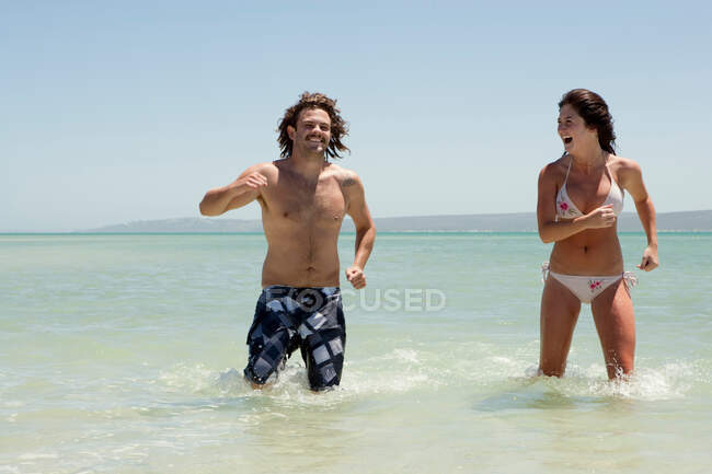 Casal brincando na água na praia — Fotografia de Stock