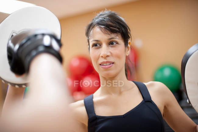 Жінка штовхає бокс в спортзалі, вибірковий фокус — стокове фото