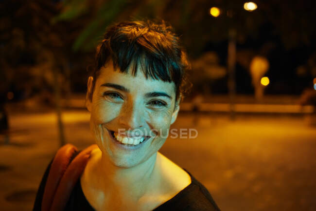 Woman by night smiling to camera — Stock Photo