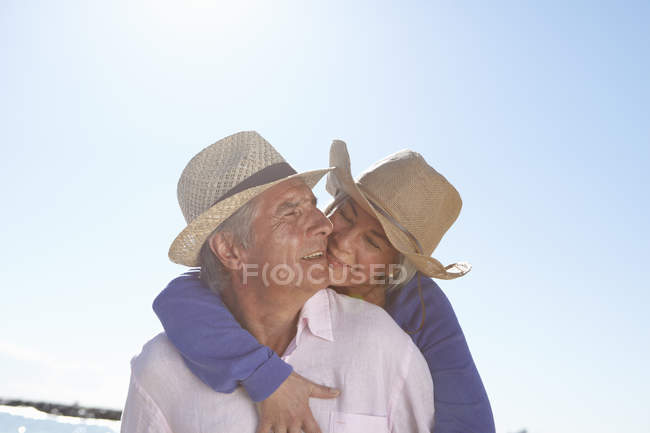 Coppia che indossa cappelli di paglia sulla spiaggia — Foto stock