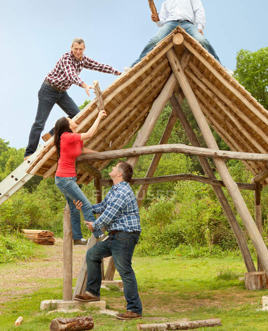 Pessoas construindo log hut juntos — Fotografia de Stock