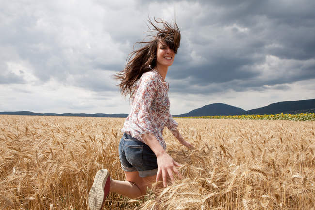 Mujer adulta corriendo por el campo de trigo - foto de stock