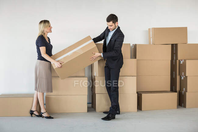 Homme d'affaires et femme soulevant la boîte en carton — Photo de stock