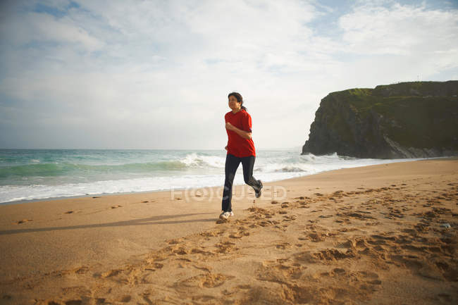 Femme courant sur la plage — Photo de stock