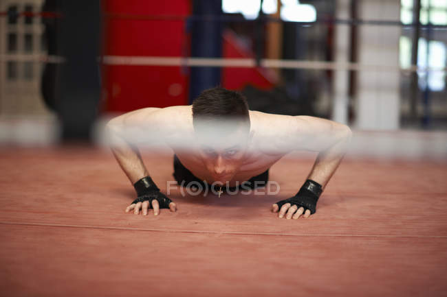Boxer doing push-ups in boxing ring — Stock Photo