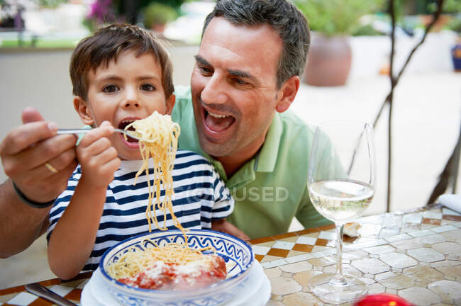 Pai e filho comendo espaguete — Fotografia de Stock