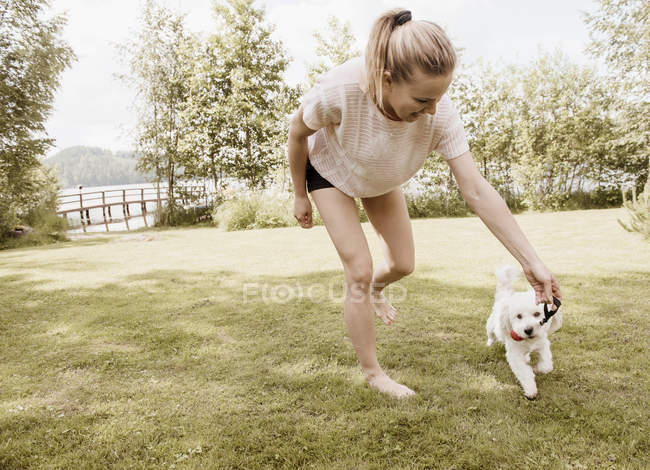 Femme jouant dans le jardin avec un chien en coton de tulear, Orivesi, Finlande — Photo de stock