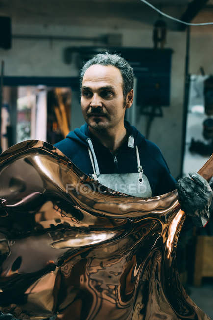 Metalworker holding copper product in forge workshop — Stock Photo