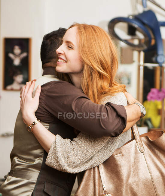 Peluquería masculina abrazando cliente femenino en peluquería - foto de stock
