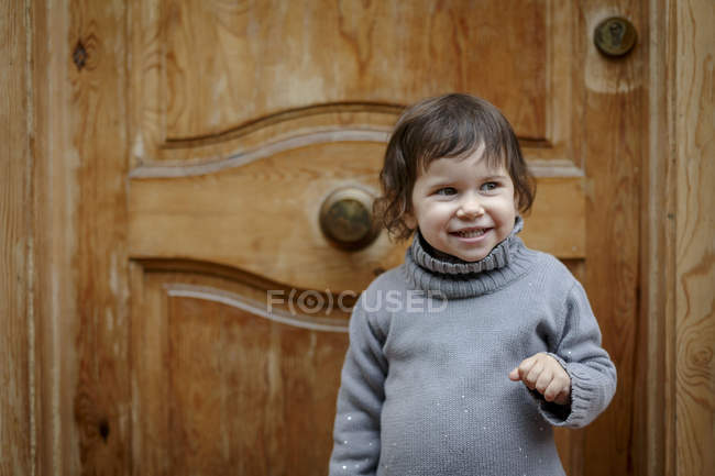 Mädchen vor Holztür lächelt — Stockfoto