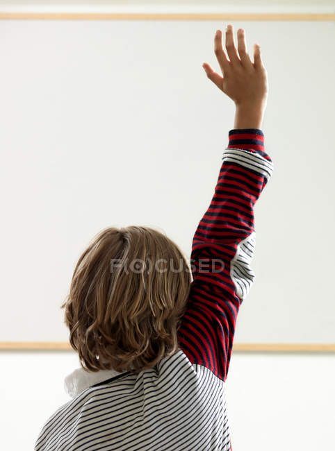 Visão traseira do menino levantando a mão na sala de aula — Fotografia de Stock