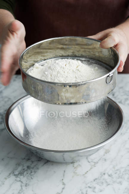 Imagen recortada de Chef tamizar harina en un tazón - foto de stock