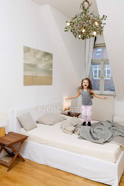 Gritando menina pulando na cama — Fotografia de Stock