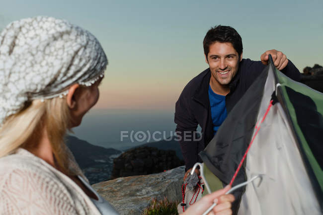 Couple setting up tent on hillside — Stock Photo