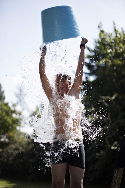 Junge schüttet Eimer Wasser auf sich — Stockfoto