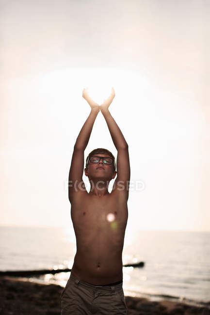 Teenage boy cupping hands around sun — Stock Photo