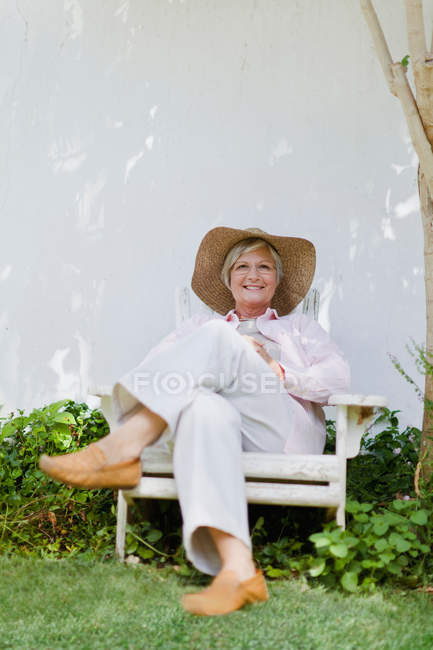 Mujer mayor relajándose en el patio trasero - foto de stock