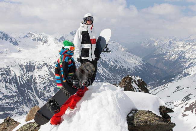 Snowboarders en la cima de una montaña rocosa - foto de stock