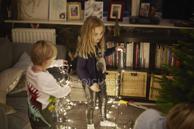 Young brother and sister untangling christmas lights — Stock Photo