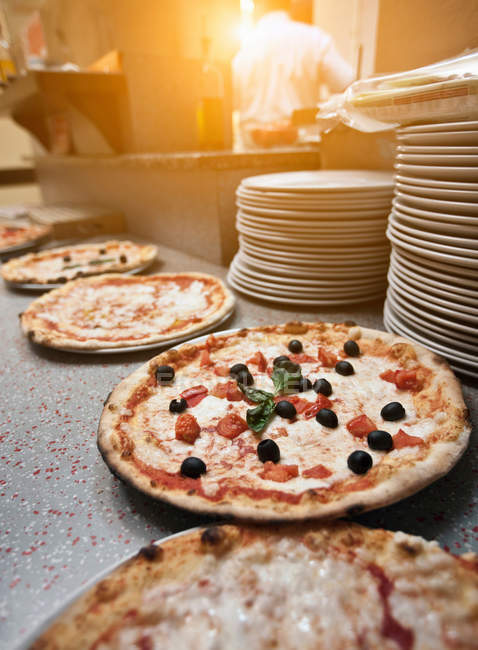 Appetitlich gekochte Pizzen auf der Theke in der Küche — Stockfoto