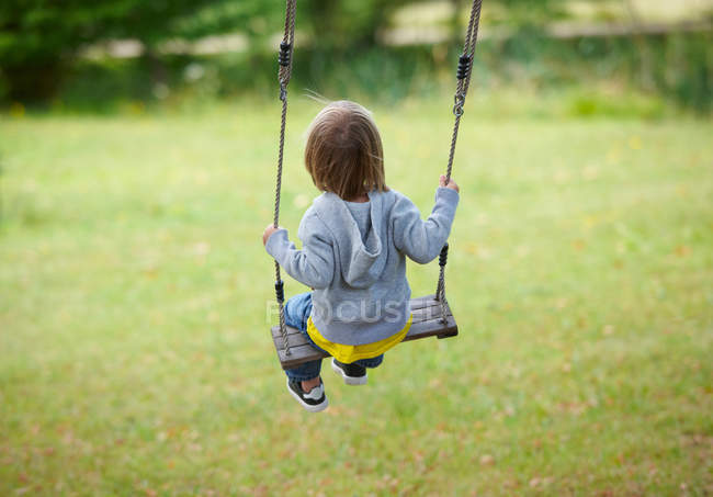 Children sitting on swing in backyard — Stock Photo