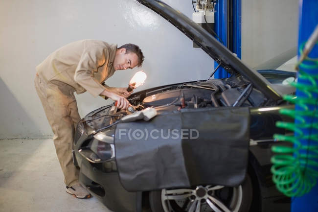 Mécanicien travaillant sur le moteur de voiture dans le garage — Photo de stock
