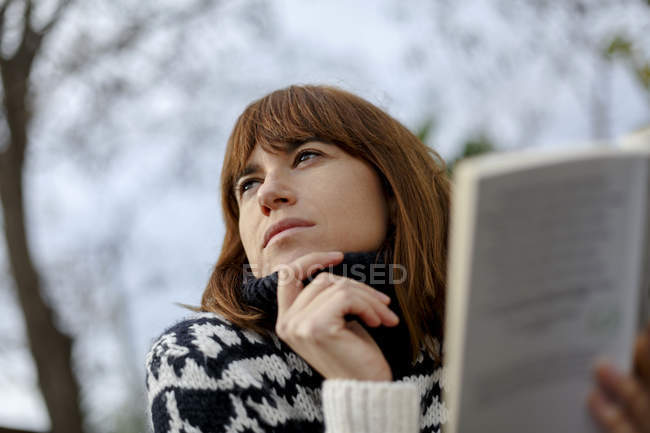 Woman holding book looking away — Stock Photo