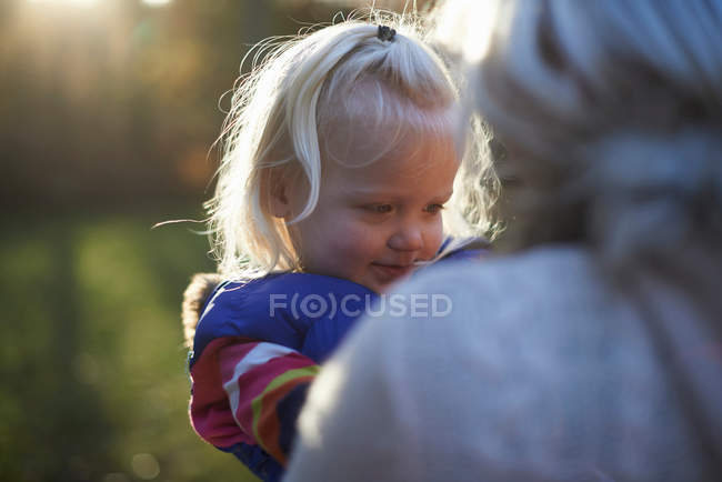 Menina da criança com a mãe ao ar livre na luz solar, close-up — Fotografia de Stock