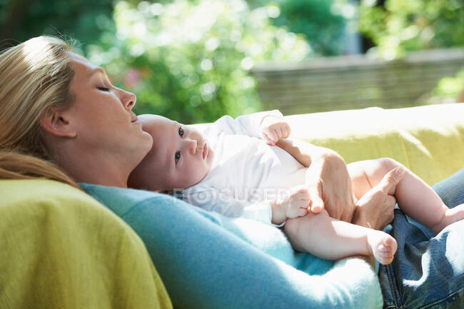 Sorridente madre rilassante con il bambino — Foto stock
