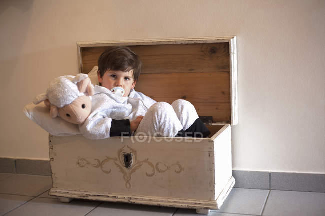 Portrait of male toddler ready for bed in small wooden trunk — Stock Photo