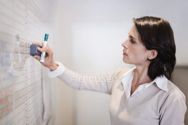 Porträt einer Geschäftsfrau beim Löschen des Whiteboards — Stockfoto