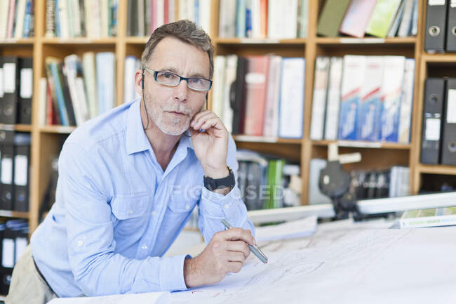 Businessman reading blueprints in office — Stock Photo