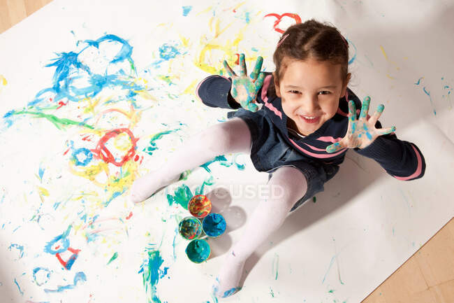 Девочка играет с краской для пальцев — стоковое фото