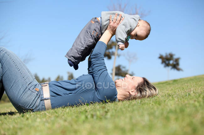 Жінка грає з дитиною в траві — стокове фото