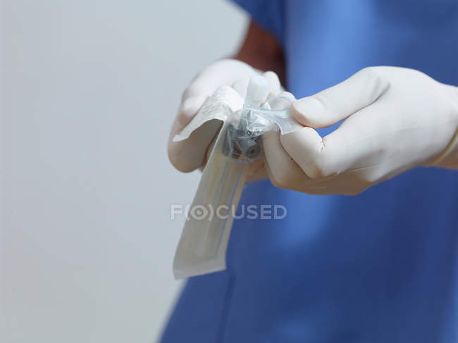 Abgeschnittenes Bild des Chirurgen in Handschuhen beim Öffnen der Packung — Stockfoto