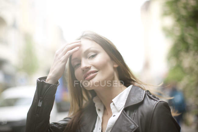 Portrait of beautiful woman with long brown hair on city street — Stock Photo