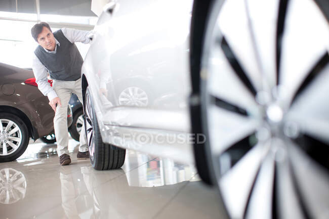 Mitte erwachsener Mann kontrolliert Auto im Verkaufsraum — Stockfoto