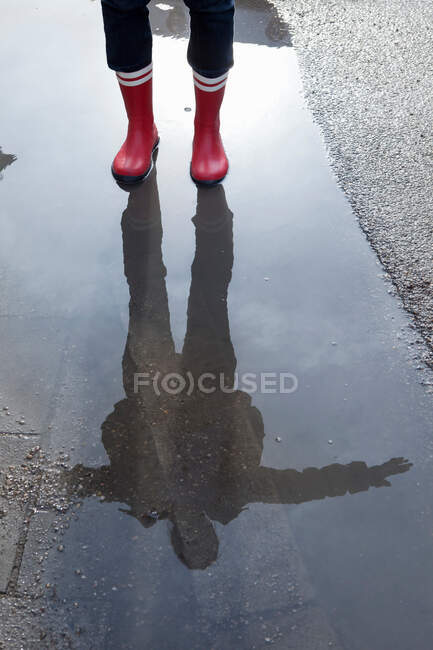 Reflexão de uma mulher em uma poça — Fotografia de Stock